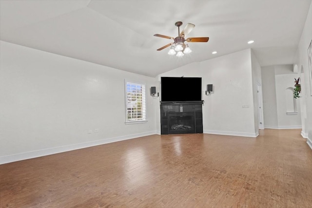 unfurnished living room featuring ceiling fan, a fireplace, wood-type flooring, and lofted ceiling