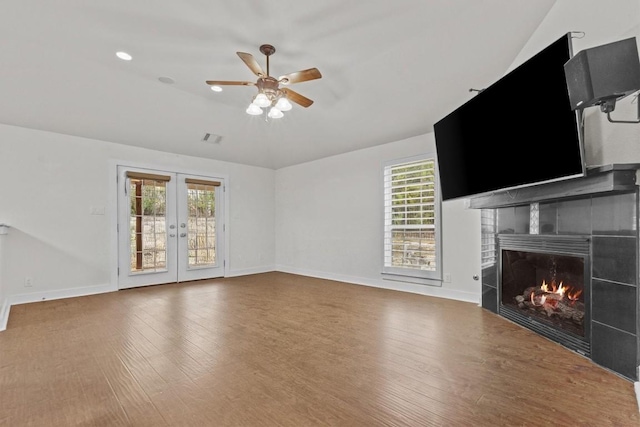 unfurnished living room featuring french doors, ceiling fan, wood-type flooring, a fireplace, and lofted ceiling