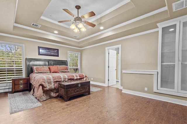 bedroom featuring a raised ceiling, ceiling fan, wood-type flooring, and ornamental molding