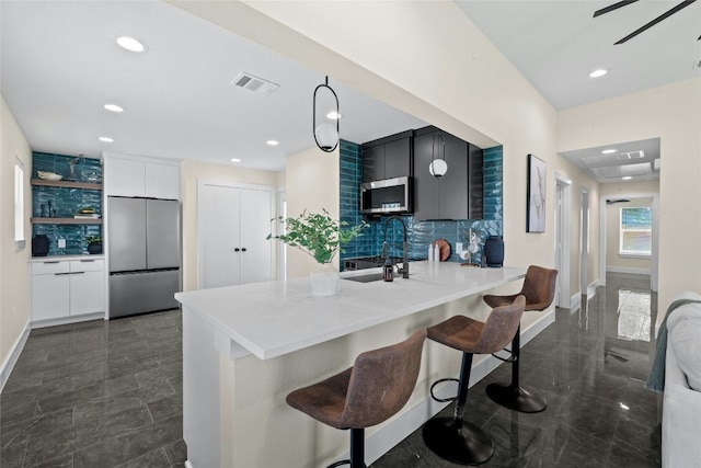 kitchen with kitchen peninsula, appliances with stainless steel finishes, a kitchen breakfast bar, tasteful backsplash, and sink