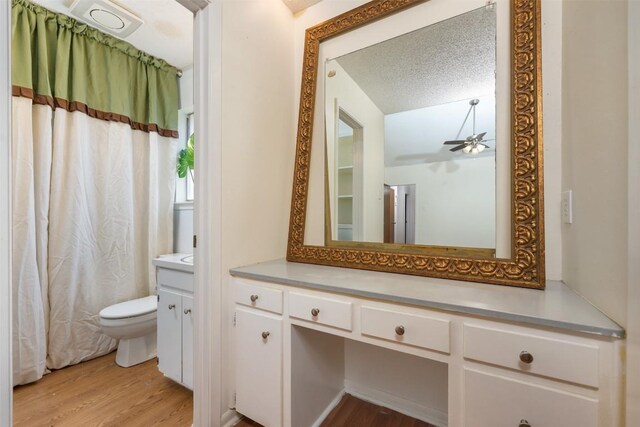 bathroom with ceiling fan, a textured ceiling, toilet, vanity, and hardwood / wood-style flooring