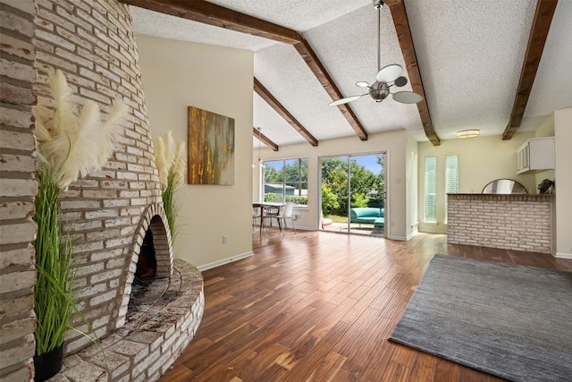 unfurnished living room featuring hardwood / wood-style floors, lofted ceiling with beams, a fireplace, and a textured ceiling