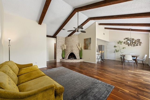 living room featuring ceiling fan with notable chandelier, a brick fireplace, a textured ceiling, beamed ceiling, and dark hardwood / wood-style flooring