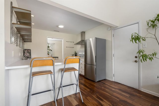 kitchen with white range, stainless steel refrigerator, dark wood-type flooring, and wall chimney range hood