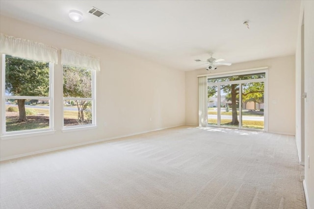 carpeted empty room featuring a wealth of natural light and ceiling fan