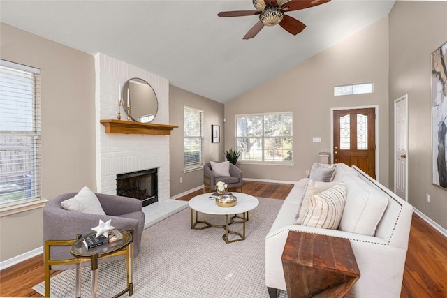 living room with ceiling fan, wood-type flooring, vaulted ceiling, and a brick fireplace