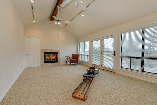 unfurnished room with high vaulted ceiling, a tile fireplace, ceiling fan, beam ceiling, and carpet floors