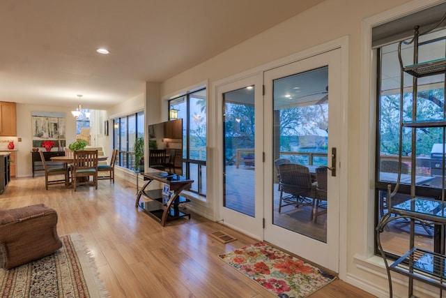 doorway to outside with light hardwood / wood-style flooring and a notable chandelier