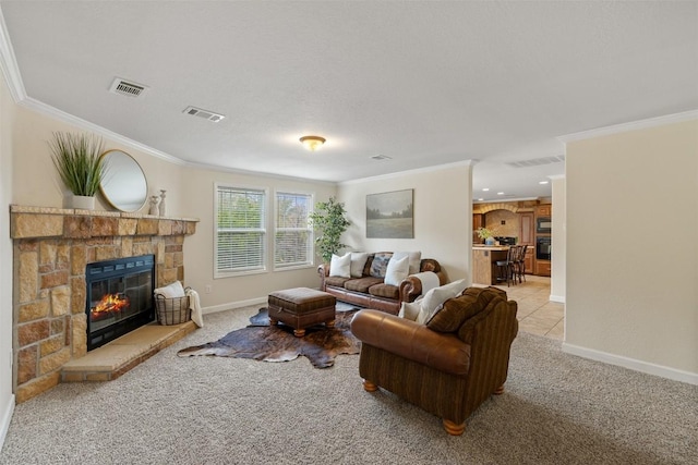 carpeted living room featuring visible vents, crown molding, a stone fireplace, and baseboards