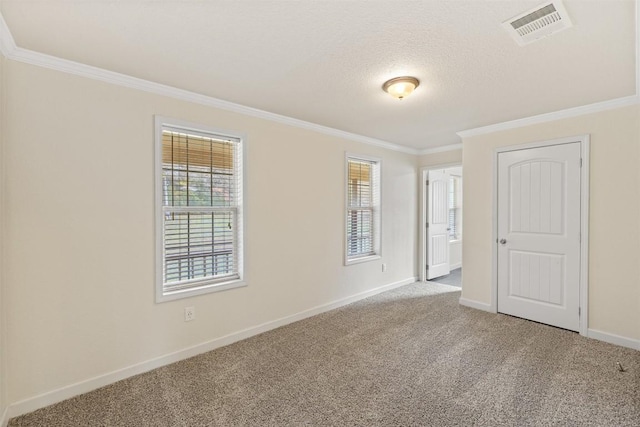 carpeted spare room with baseboards, visible vents, a textured ceiling, and ornamental molding