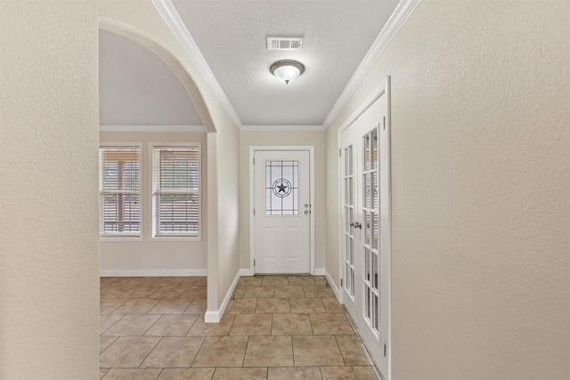 entryway featuring a textured ceiling, a textured wall, visible vents, baseboards, and ornamental molding