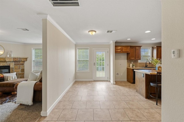 kitchen featuring a fireplace, visible vents, light countertops, ornamental molding, and brown cabinets