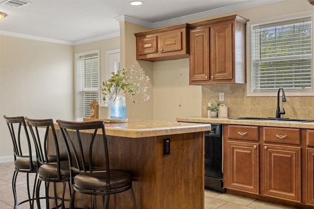 kitchen featuring a breakfast bar, a kitchen island, a sink, light countertops, and decorative backsplash