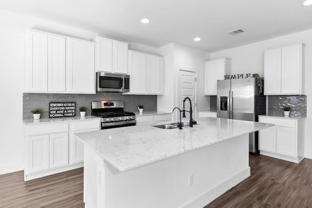 kitchen with white cabinets, sink, appliances with stainless steel finishes, and an island with sink