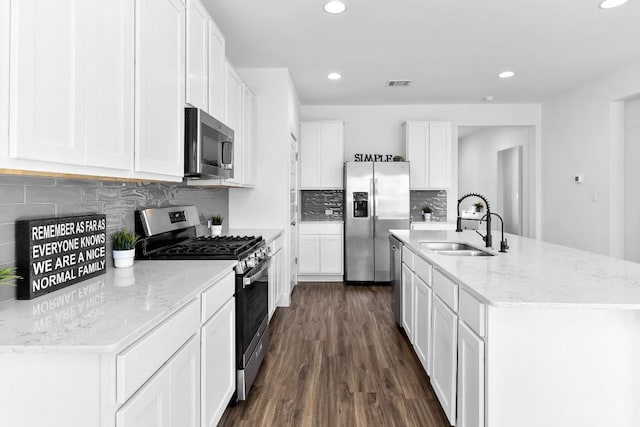 kitchen with a sink, visible vents, white cabinets, appliances with stainless steel finishes, and an island with sink