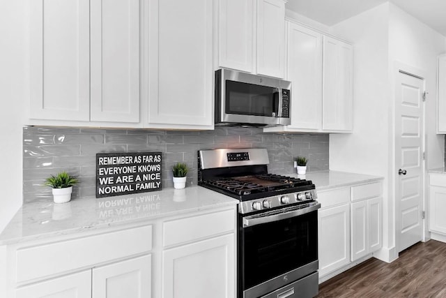 kitchen with dark wood-style flooring, white cabinetry, stainless steel appliances, and light stone counters