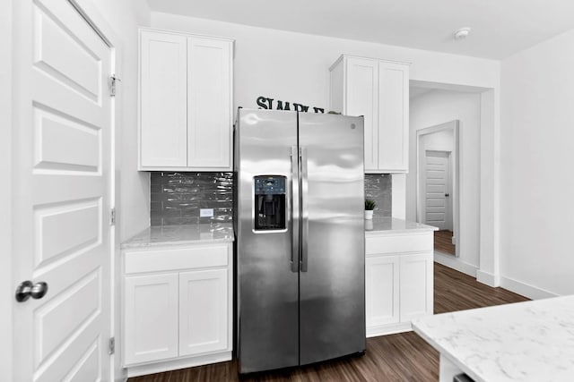 kitchen with tasteful backsplash, stainless steel fridge, white cabinetry, and dark wood-type flooring