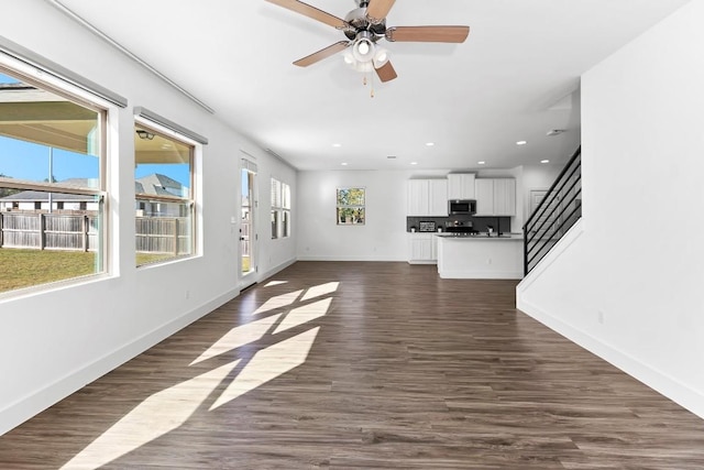 unfurnished living room with dark wood-style floors, recessed lighting, stairway, and baseboards