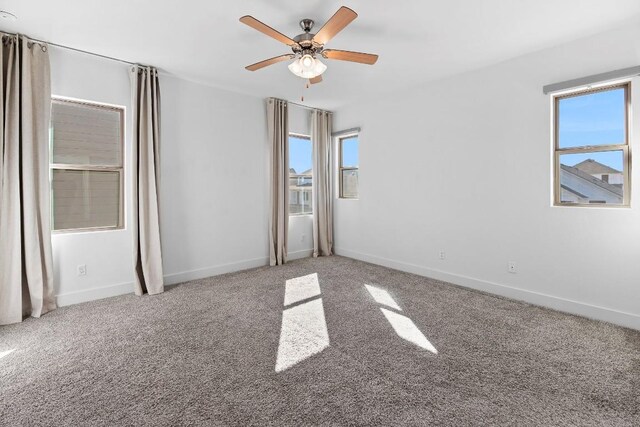 empty room featuring ceiling fan, carpet, and a healthy amount of sunlight