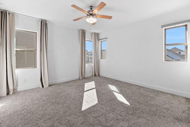 carpeted empty room with baseboards and a ceiling fan