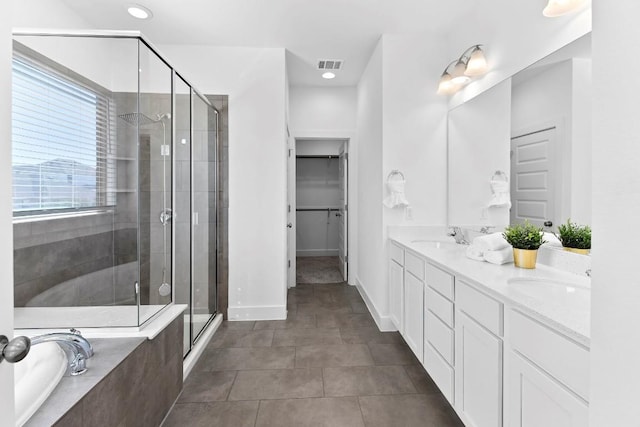 full bathroom with a sink, a stall shower, a walk in closet, and visible vents