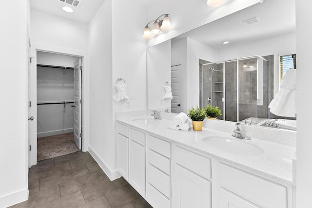 bathroom featuring a sink, visible vents, double vanity, a stall shower, and a walk in closet