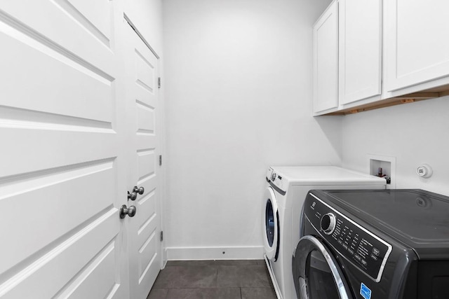 laundry area featuring cabinet space, dark tile patterned floors, baseboards, and separate washer and dryer