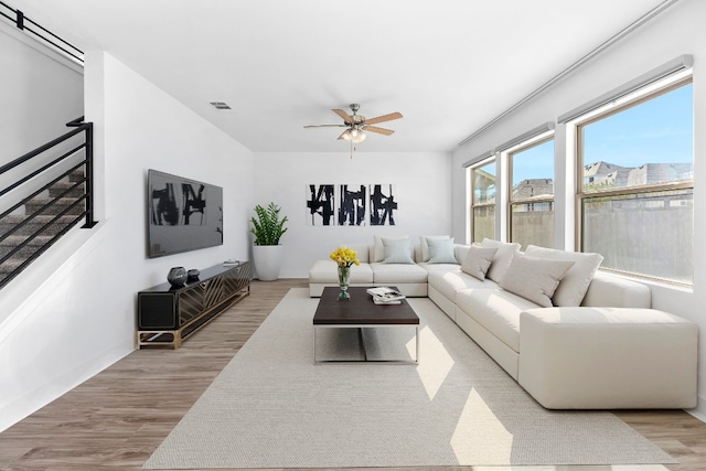 living area featuring ceiling fan, stairway, visible vents, and light wood-style floors