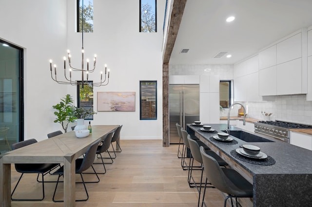 kitchen with sink, a kitchen breakfast bar, beamed ceiling, light hardwood / wood-style floors, and high quality appliances