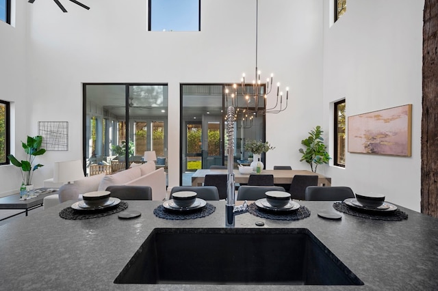 dining space featuring ceiling fan with notable chandelier and a towering ceiling