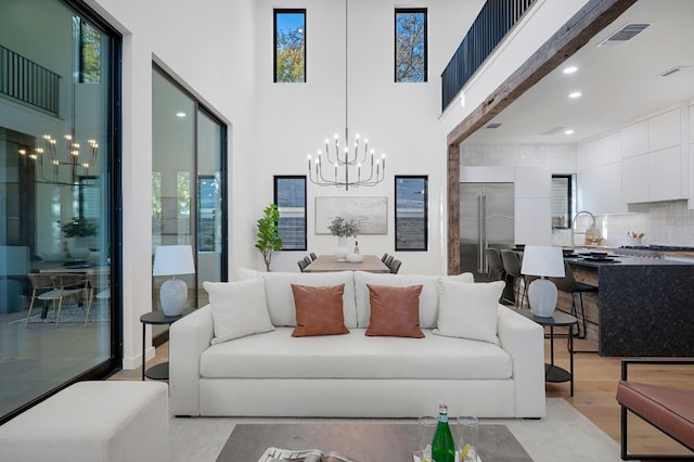 living room with light hardwood / wood-style flooring, a towering ceiling, and a chandelier