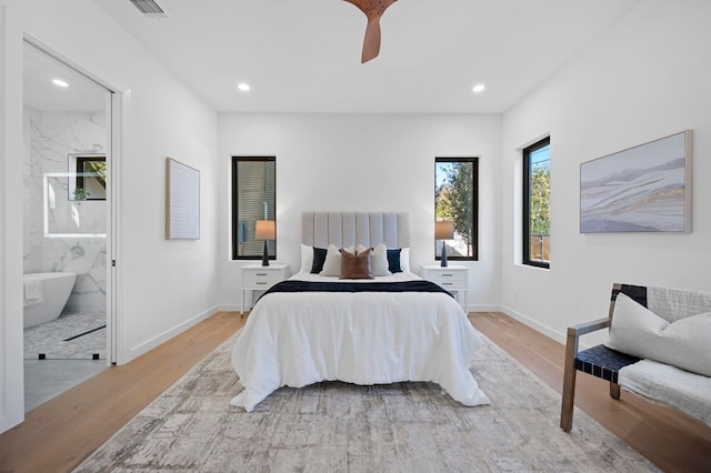 bedroom with ensuite bathroom, ceiling fan, and light wood-type flooring