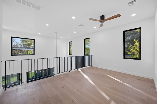 spare room with ceiling fan, a healthy amount of sunlight, and light hardwood / wood-style floors