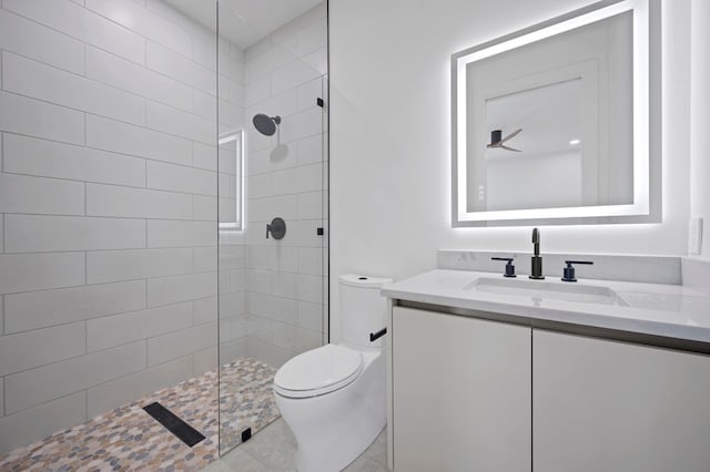 bathroom with vanity, ceiling fan, toilet, and tiled shower