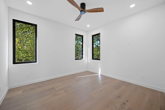 spare room with a wealth of natural light, ceiling fan, and light hardwood / wood-style floors