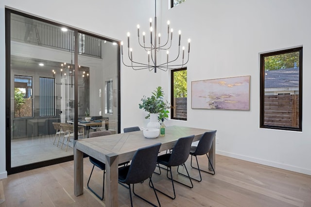 dining space featuring a high ceiling, light hardwood / wood-style flooring, and a healthy amount of sunlight