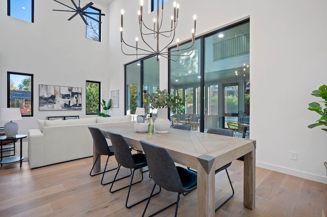 dining area with a wealth of natural light, light hardwood / wood-style floors, and a high ceiling