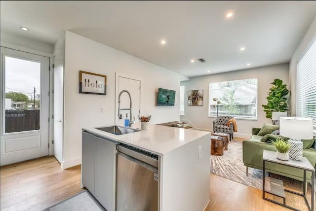 kitchen featuring a kitchen island with sink, dishwasher, light hardwood / wood-style floors, and sink