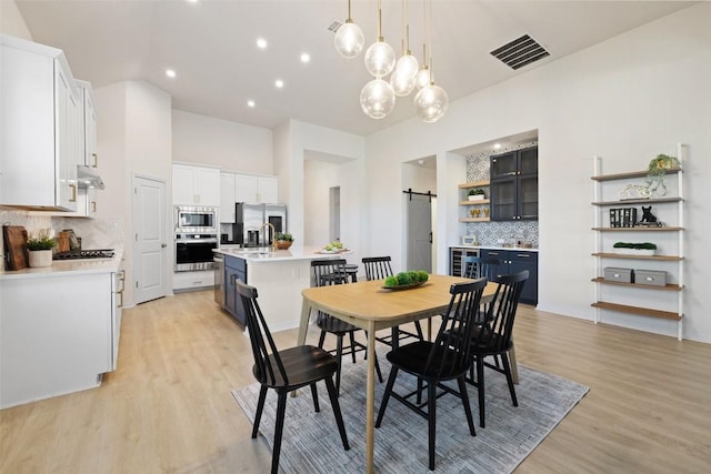 dining area with beverage cooler, a barn door, and light hardwood / wood-style floors