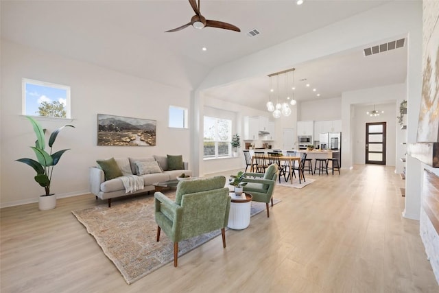 living room featuring light hardwood / wood-style floors, plenty of natural light, and ceiling fan with notable chandelier