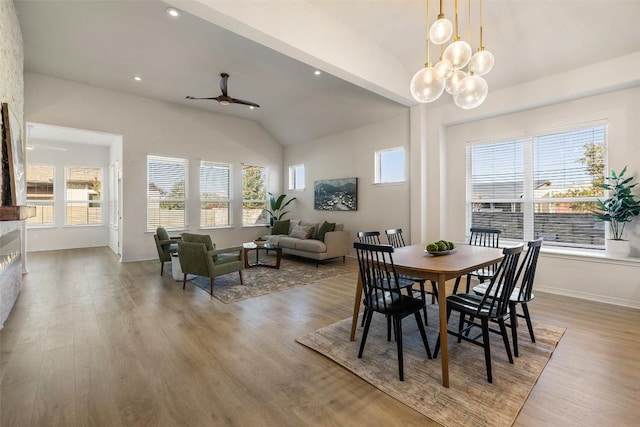 dining space featuring lofted ceiling, ceiling fan with notable chandelier, and wood-type flooring