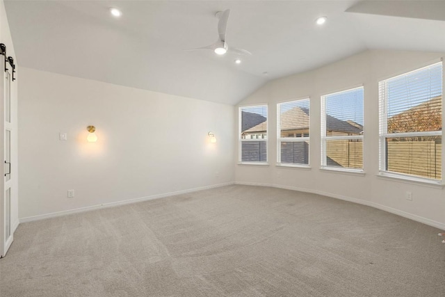 unfurnished room featuring lofted ceiling, ceiling fan, plenty of natural light, and a barn door