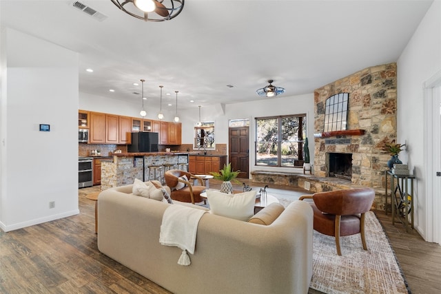 living room with hardwood / wood-style flooring, ceiling fan, sink, and a fireplace