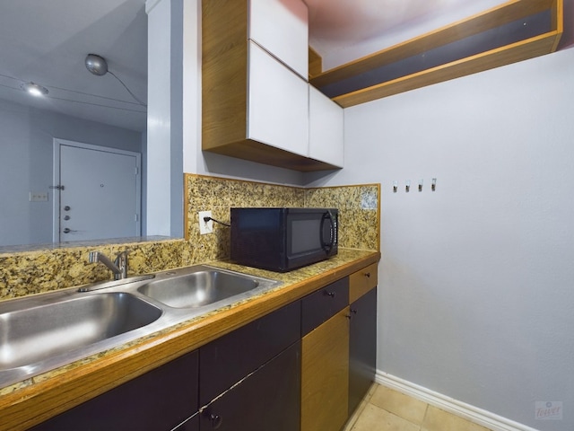 kitchen with sink, tasteful backsplash, white cabinetry, and light tile patterned flooring