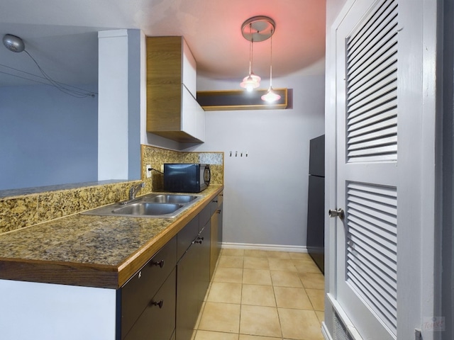 kitchen featuring dark brown cabinetry, sink, black appliances, pendant lighting, and light tile patterned flooring