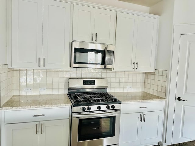 kitchen featuring white cabinets, backsplash, light stone countertops, and stainless steel appliances