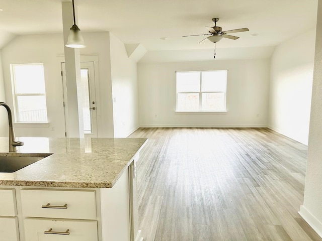 kitchen featuring sink, hanging light fixtures, lofted ceiling, white cabinets, and light wood-type flooring