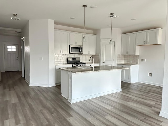 kitchen with a kitchen island with sink, hardwood / wood-style floors, white cabinets, and stainless steel appliances