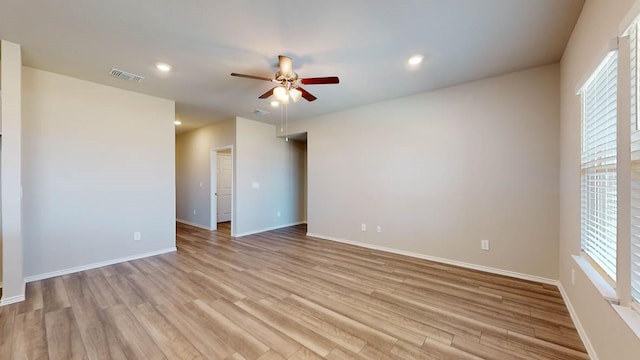 spare room featuring light wood-type flooring, ceiling fan, and a healthy amount of sunlight