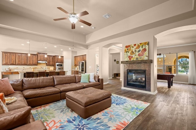 living room with dark hardwood / wood-style floors, ceiling fan, a towering ceiling, a fireplace, and pool table